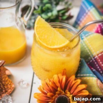 Classic screwdriver cocktail, served in pineapple shaped cocktail glass, placed next to an orange flower.