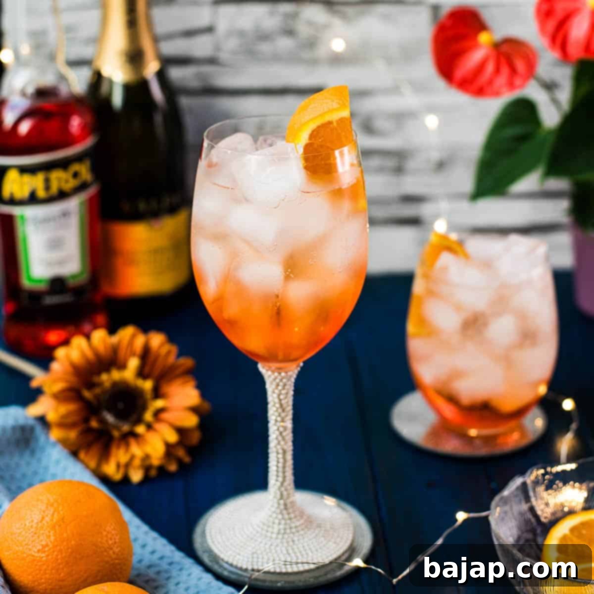 Wonderful layered Aperol Spritz! Tart and delicious! Placed on a mirror coaster on a blue wooden background.