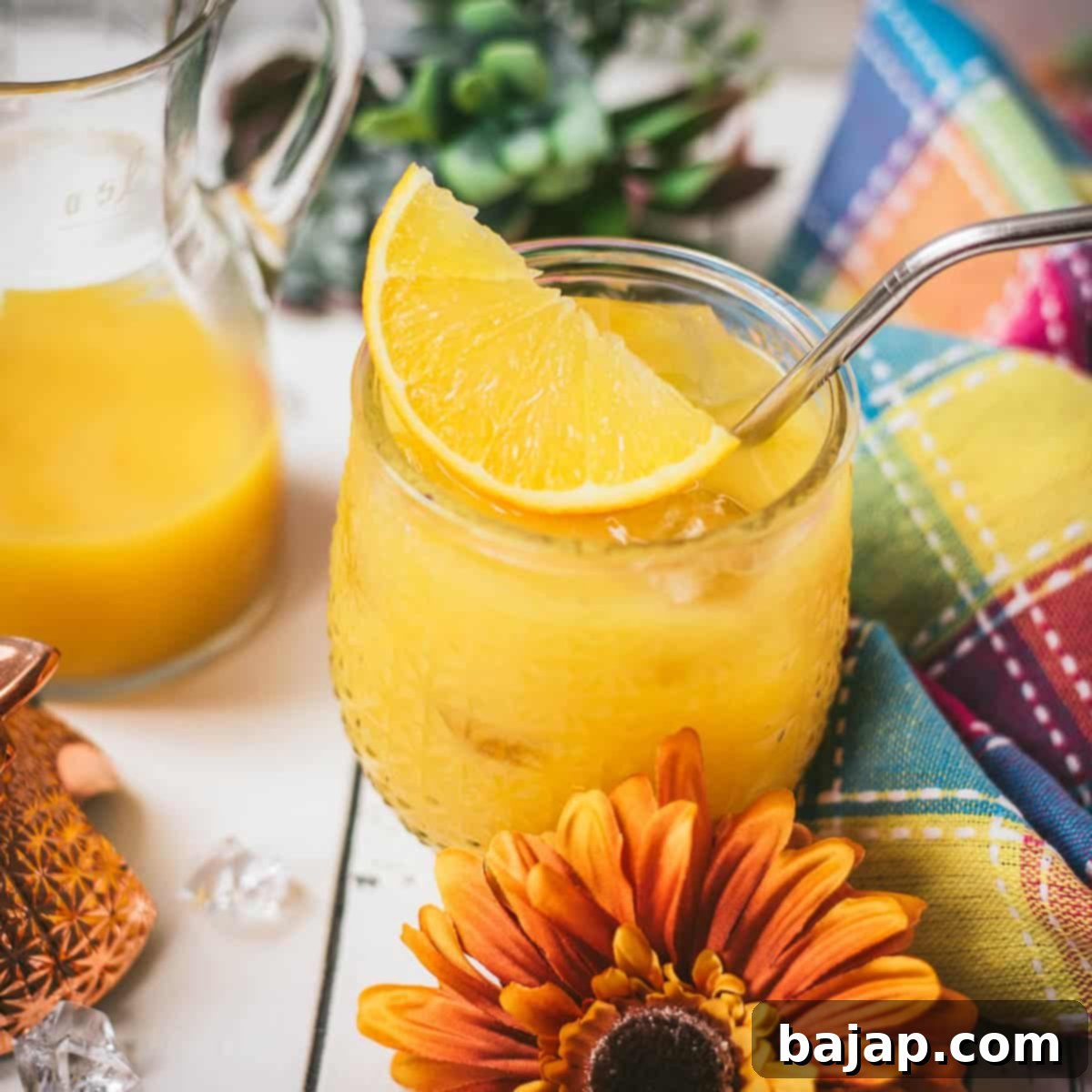 Classic screwdriver cocktail, served in pineapple shaped cocktail glass, placed next to an orange flower.
