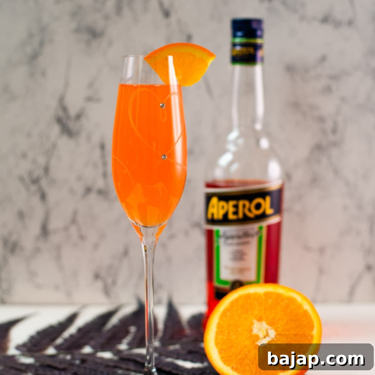 Gorgeous sparkling wine glass, with engraved heart and two crystals, filled with delicious Aperol Mimosa. Placed on heartshaped black slate coaster.
