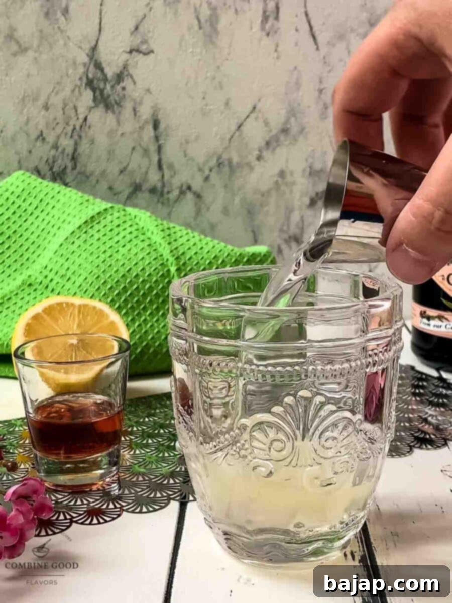 Pouring gin into the cocktail shaker with lemon juice and simple syrup.