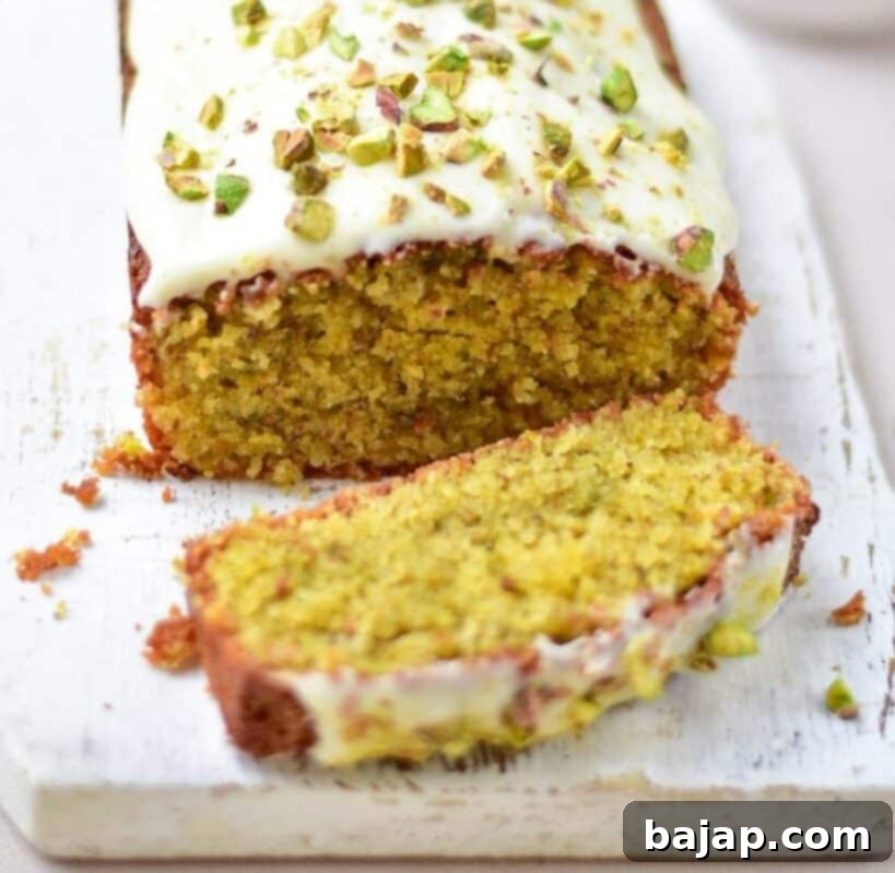 A slice of Italian Almond Pistachio Cake with a generous layer of cream cheese frosting.