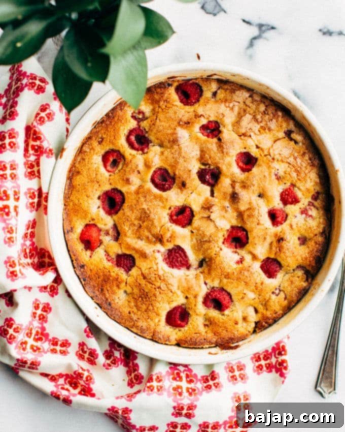 Tender pistachio-raspberry cake, or buckle, dimpled with fresh fruit and ready to be served.