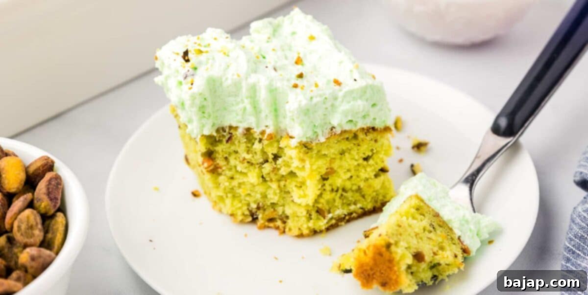 A slice of sweet pistachio pudding cake, also known as Watergate cake, with its characteristic green color.