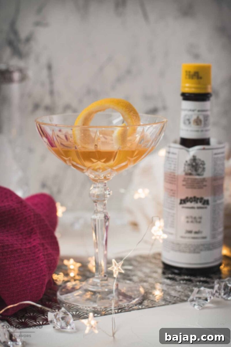 Elegant Pink Gin Cocktail in a stemmed glass, garnished with lemon zest.