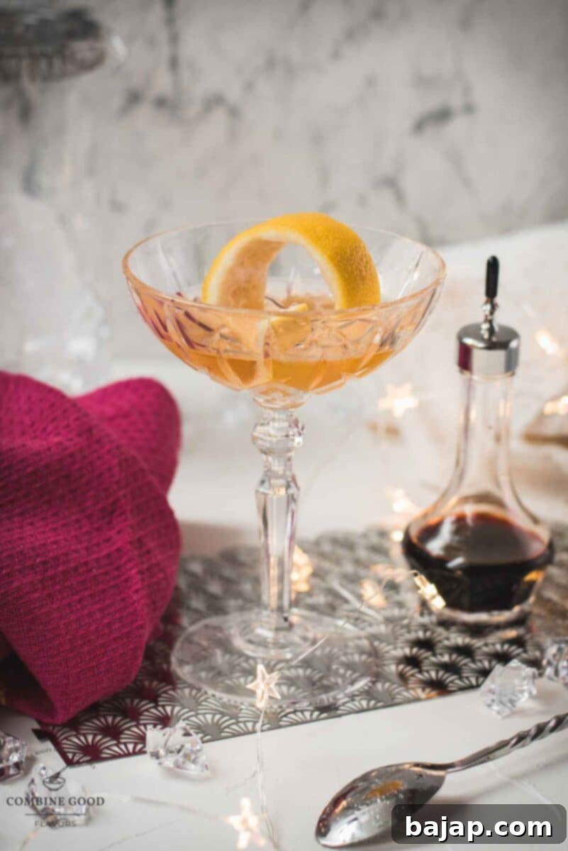 A finished elegant pink gin cocktail in a coupe glass, garnished with a perfectly twisted lemon zest.