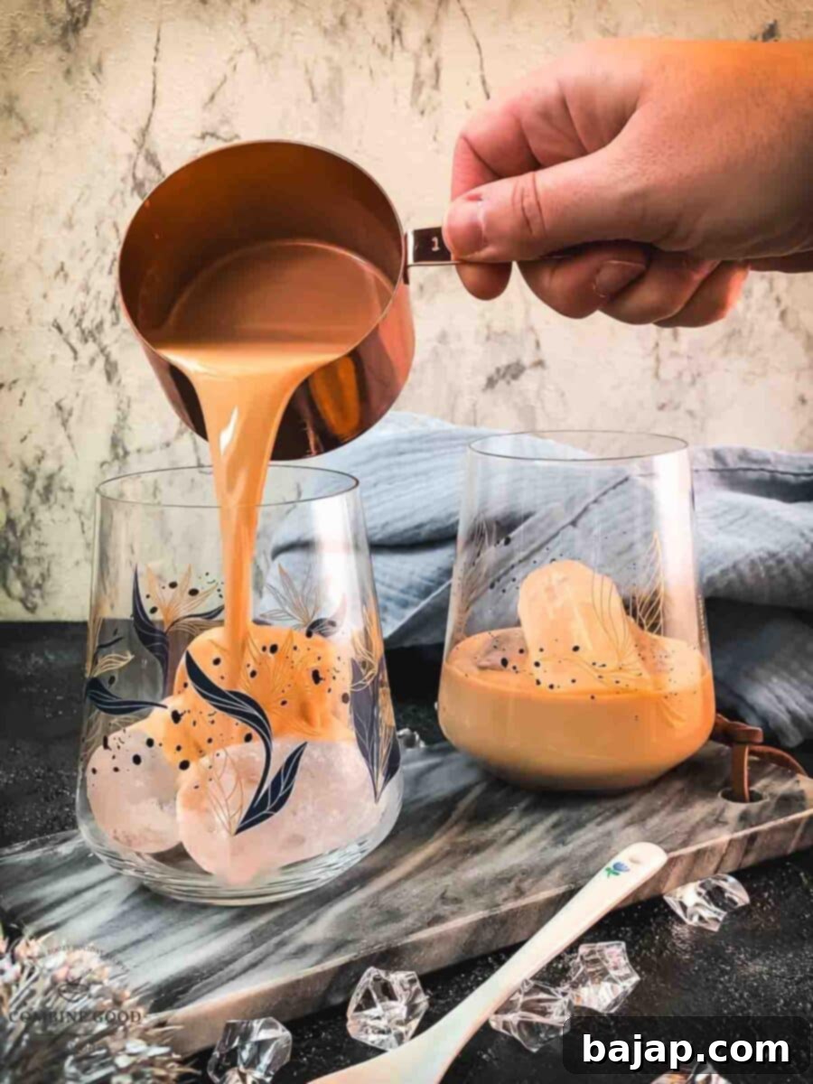Velvet Frost 4 Pouring a smooth stream of Baileys Irish Cream into a tumbler glass with ice cubes for an ideal on-the-rocks serving.