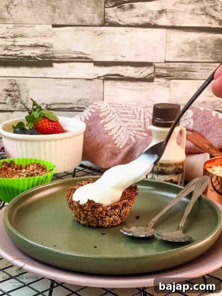 Crunchy Granola Bites 8 A spoonful of creamy natural yogurt is being added on top of a crispy granola cup, preparing it for fruit toppings.