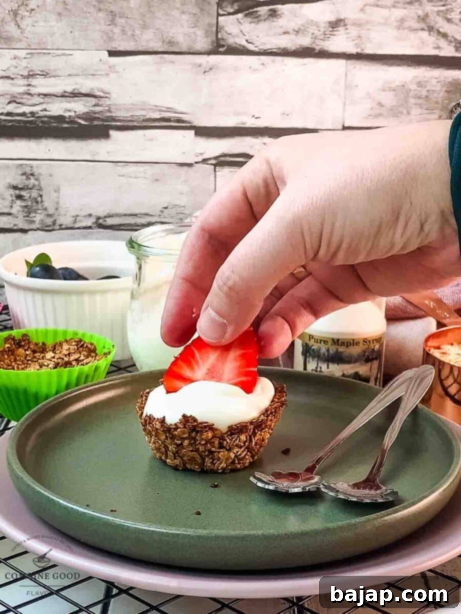 Crunchy Granola Bites 9 Sliced fresh strawberries are being carefully placed on top of the yogurt-filled granola cup, adding color and sweetness.