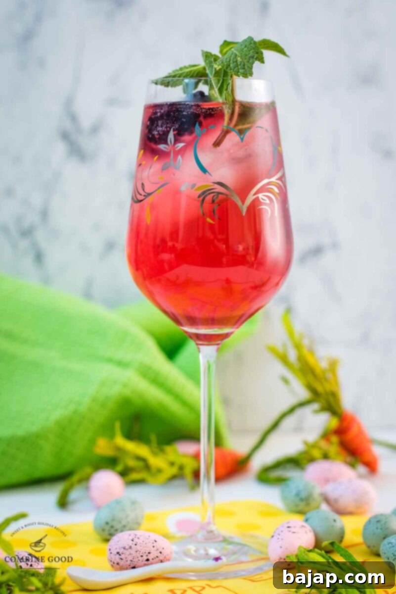 Cute white wine glass, filled with a delicious Blackberry Raspberry Easter Spritz. Garnished with blackberries and mint spring.