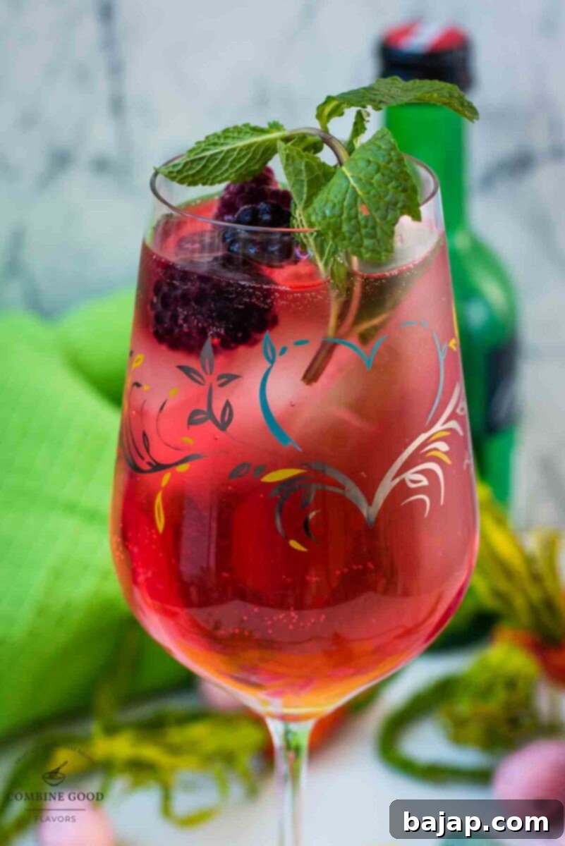 Cute white wine glass, filled with a delicious Blackberry Raspberry Easter Spritz. Garnished with blackberries and mint sprig.