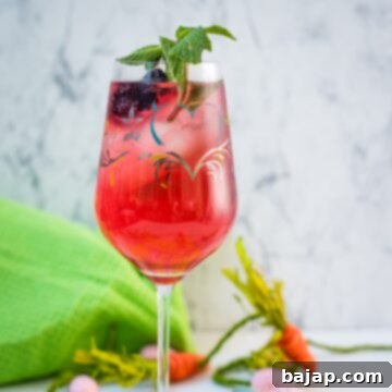 Cute white wine glass, filled with a delicious Blackberry Raspberry Easter Spritz. Garnished with blackberries and mint spring.