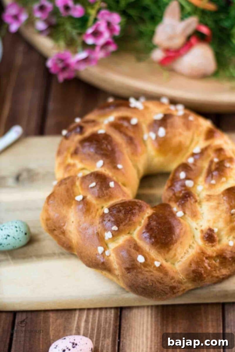 Gorgeous braided Easter bread wreath, placed on a wooden cutting board, next to Easter decoration. This visually appealing bread is soft, fluffy, and lightly sweet.