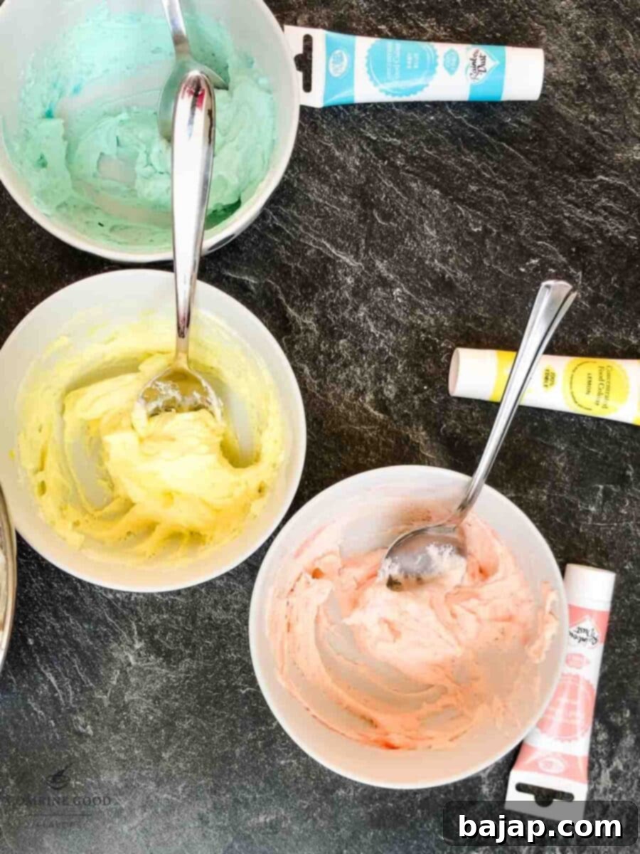 Assortment of pastel colored buttercreams in separate bowls: pink, yellow, blue, and lilac.