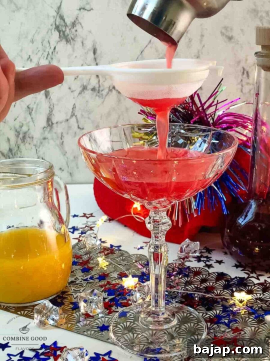 Straining the finished Berry Citrus 4th of July Margarita into a cocktail glass.