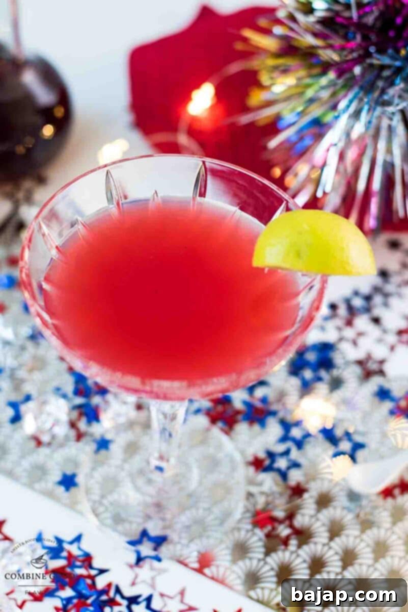 Utterly delicious Fourth of July margarita cocktail in a cocktail glass. Garnished with a lime slice and placed on white ground, covered with red, white and blue confetti stars, enhancing its festive appeal.