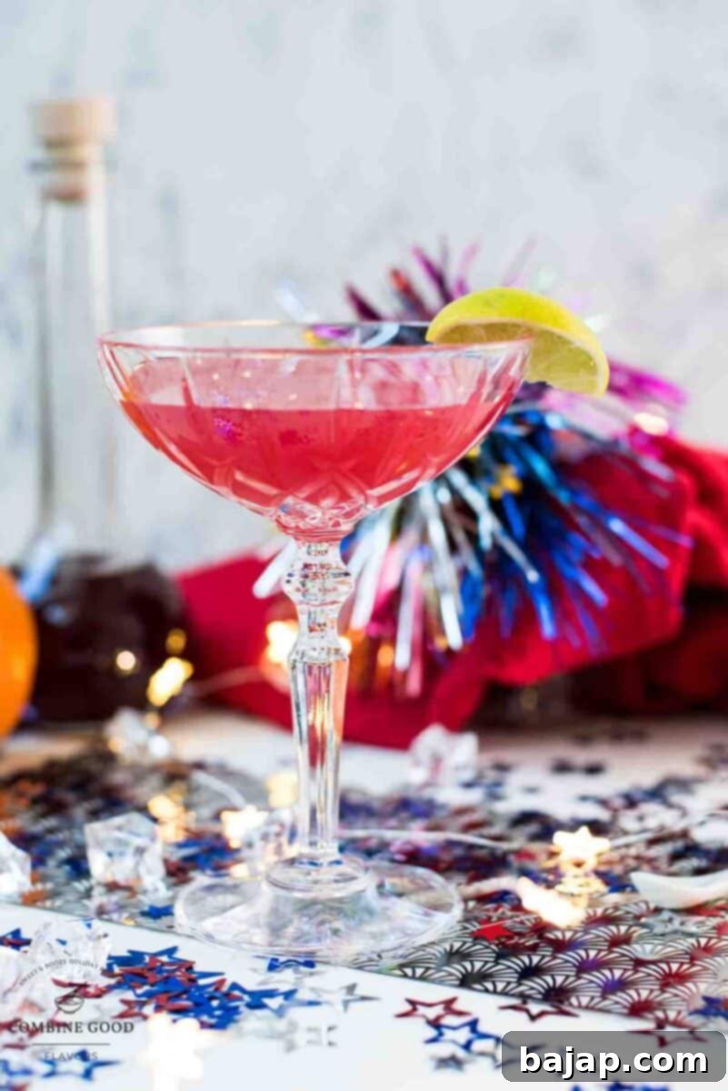 Utterly delicious Fourth of July margarita cocktail in a cocktail glass. Garnished with a lime slice and placed on white ground, covered with red, white and blue confetti stars, ready for a festive celebration.