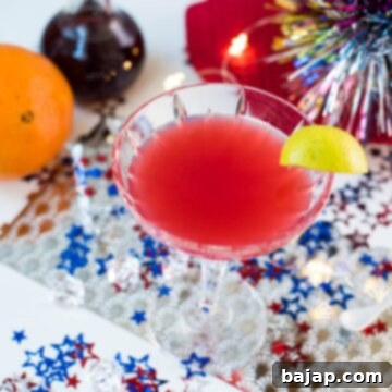 Utterly delicious Fourth of July margarita cocktail in a cocktail glass. Garnished with a lime slice and placed on white ground, covered with red, white and blue confetti stars.