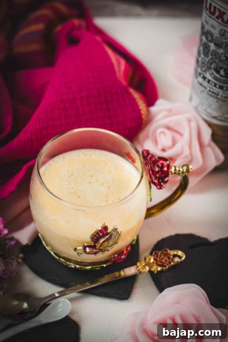 Creamy, dreamy Maraschino liqueur cocktail served in whimsical cup with red and golden butterflies and flowers. Placed on a black slate heart shaped coaster.