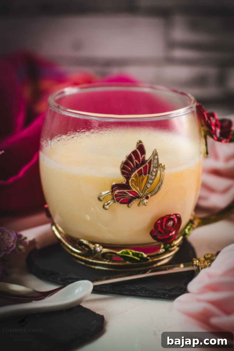 Creamy, dreamy Maraschino liqueur cocktail served in whimsical cup with red and golden butterflies and flowers. Placed on a black slate heart shaped coaster.
