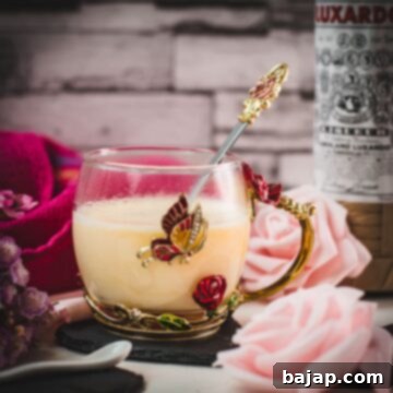 Creamy, dreamy Maraschino liqueur cocktail served in whimsical cup with red and golden butterflies and flowers. Placed on a black slate heart shaped coaster.