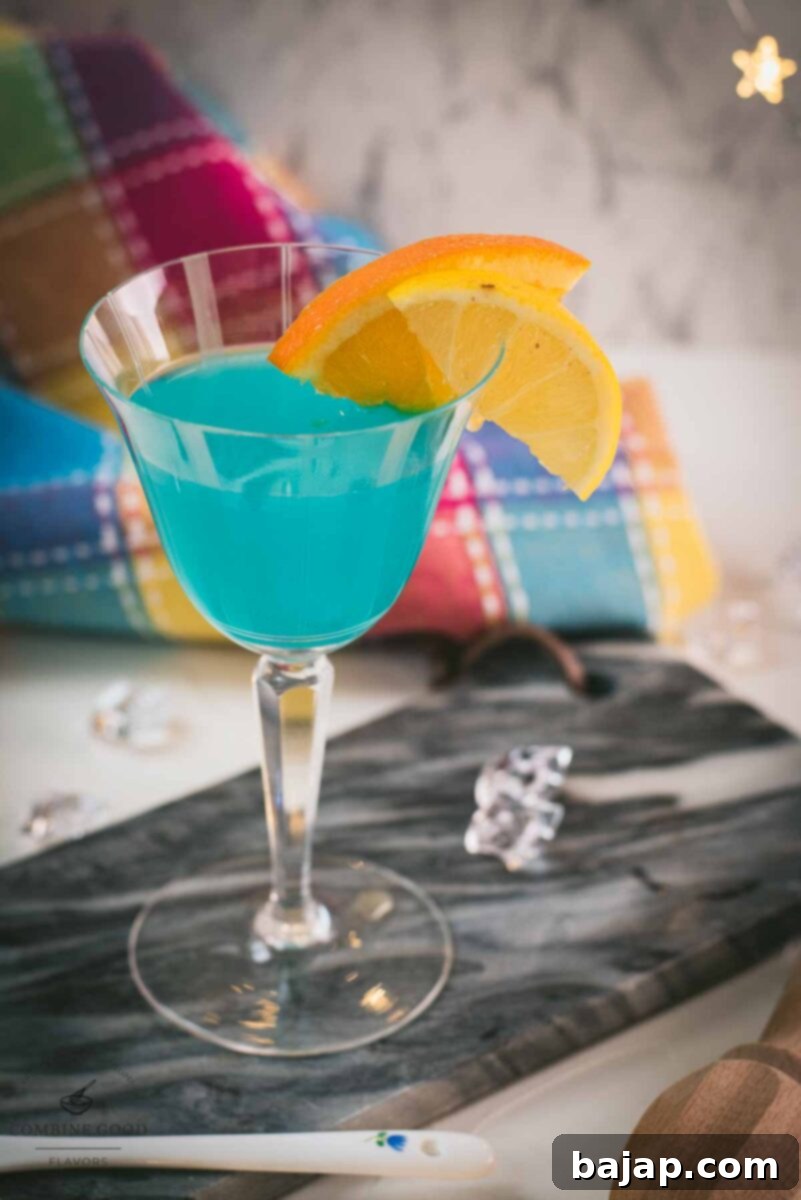 Gorgeous blue lady cocktail, served in vintage glass, garnished with an orange and an lemon slice side by side. Placed on a marbled plate.