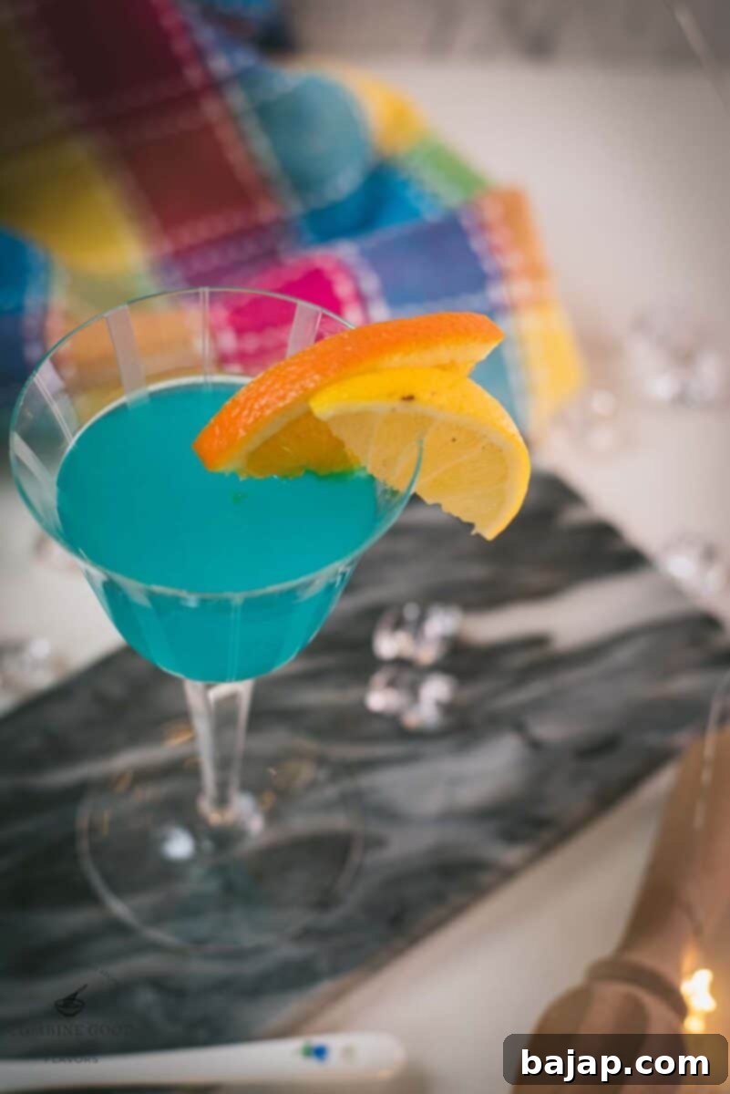 Gorgeous blue lady cocktail, served in vintage glass, garnished with an orange and an lemon slice side by side. Placed on a marbled plate.