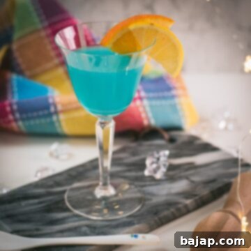 Gorgeous blue lady cocktail, served in vintage glass, garnished with an orange and an lemon slice side by side. Placed on a marbled plate.