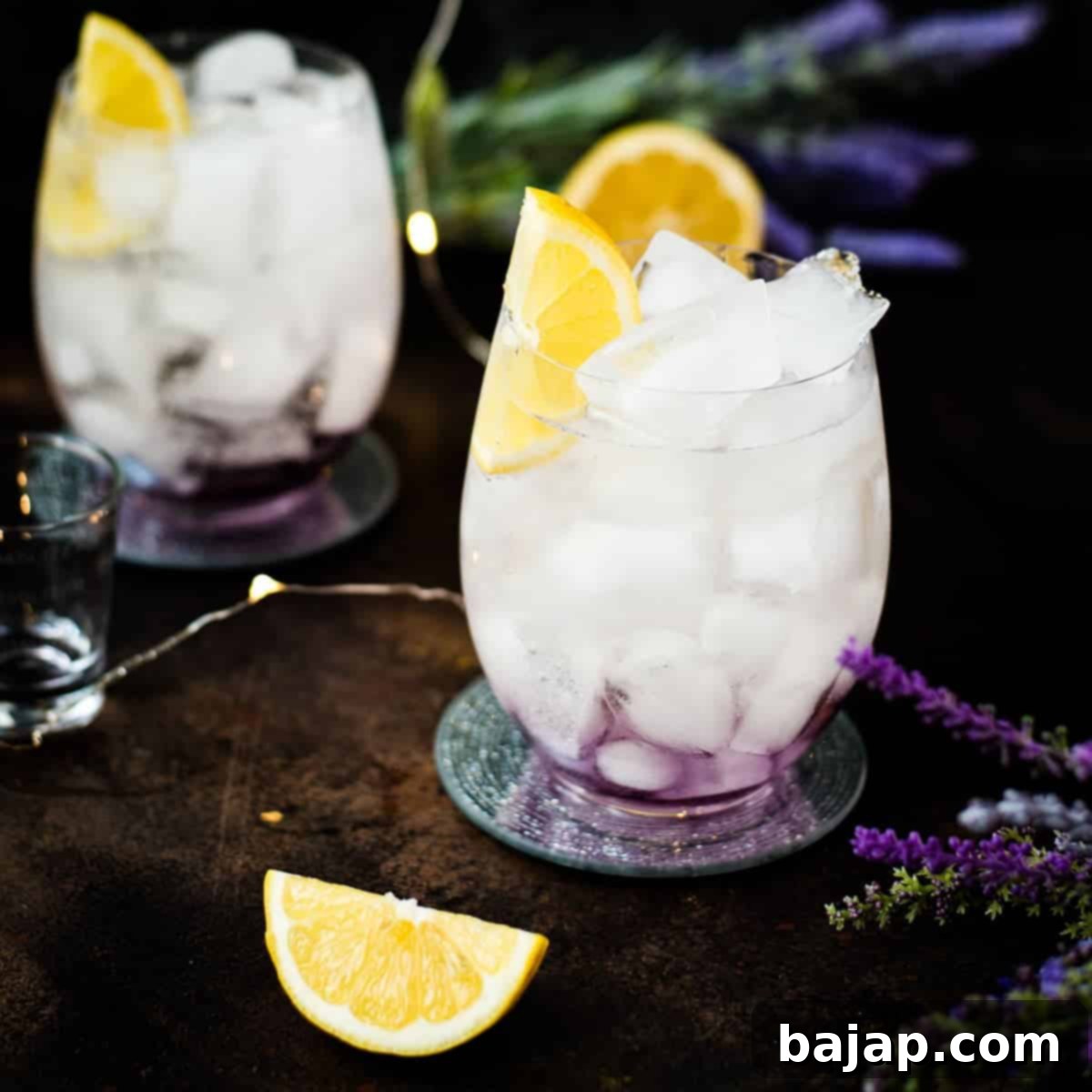Gorgeous lavender spritz, garnished with lemon wedge and placed on shimmering coaster. A delightful lavender Prosecco drink.