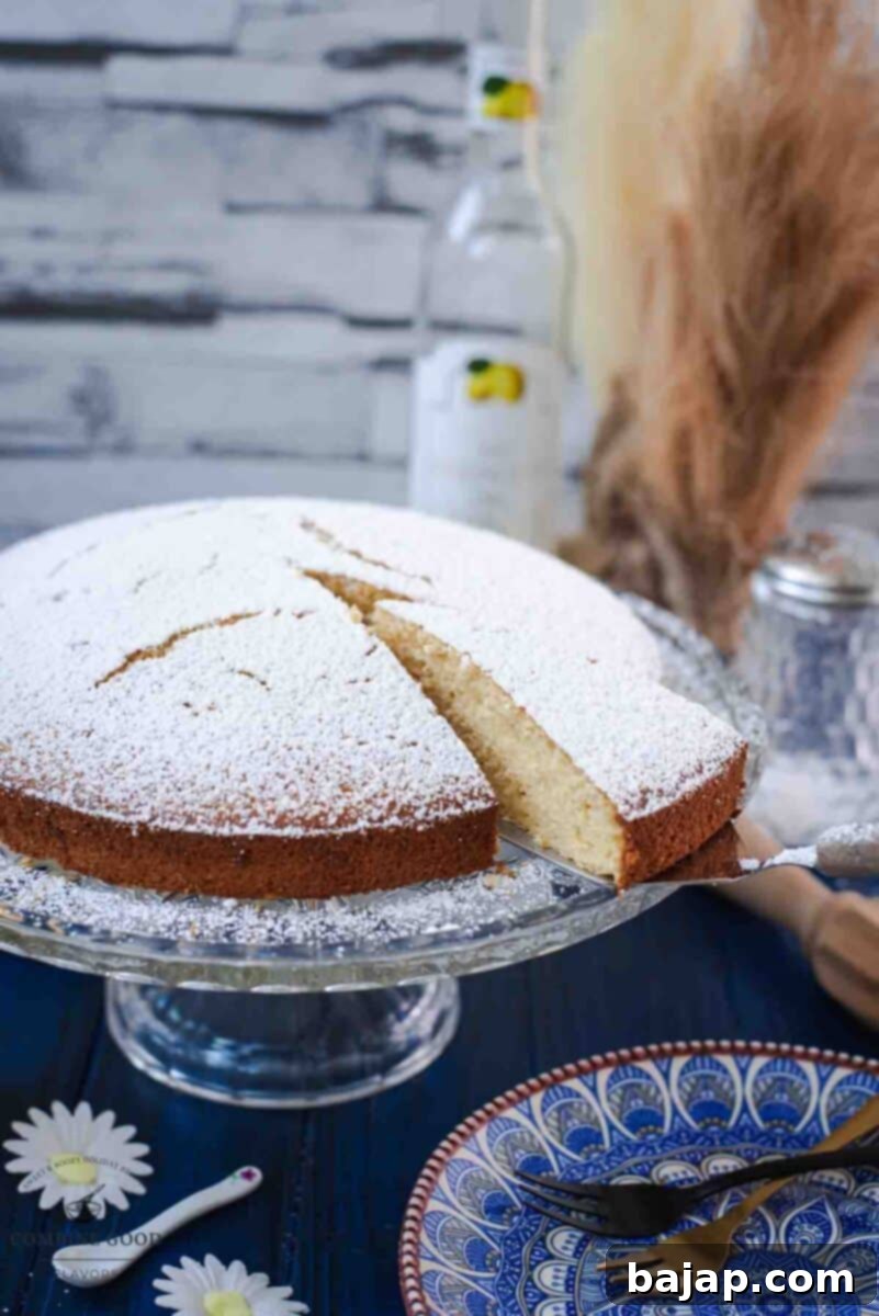 Delicious limoncello ricotta cake, sliced, on a glass cake stand.