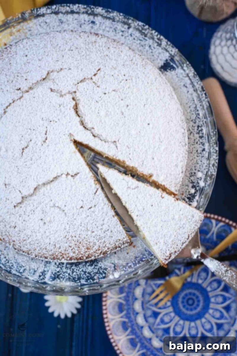 Delicious limoncello ricotta cake, sliced, on a glass cake stand.