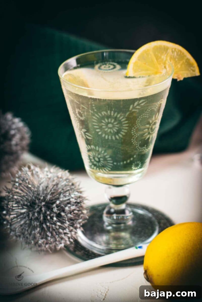 A beautifully engraved glass filled with a refreshing Blondie cocktail made with white vermouth. Garnished with a bright lemon wedge, perfect for summer.