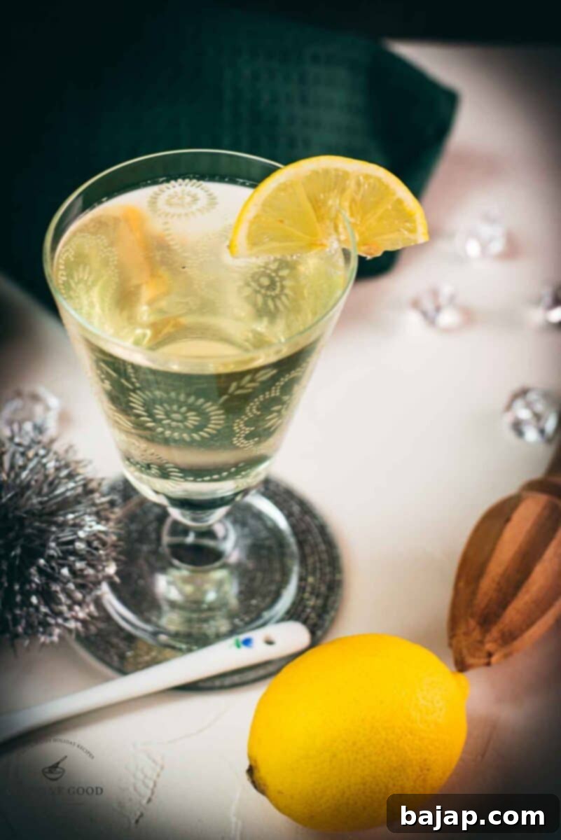 A charming glass with flower engraving, holding a delicious White Vermouth Blondie cocktail. Garnished elegantly with a lemon wedge.