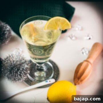 Glass with beautiful flower engraving, filled with delicious White Vermouth Blondie cocktail. Garnished with a lemon wedge.