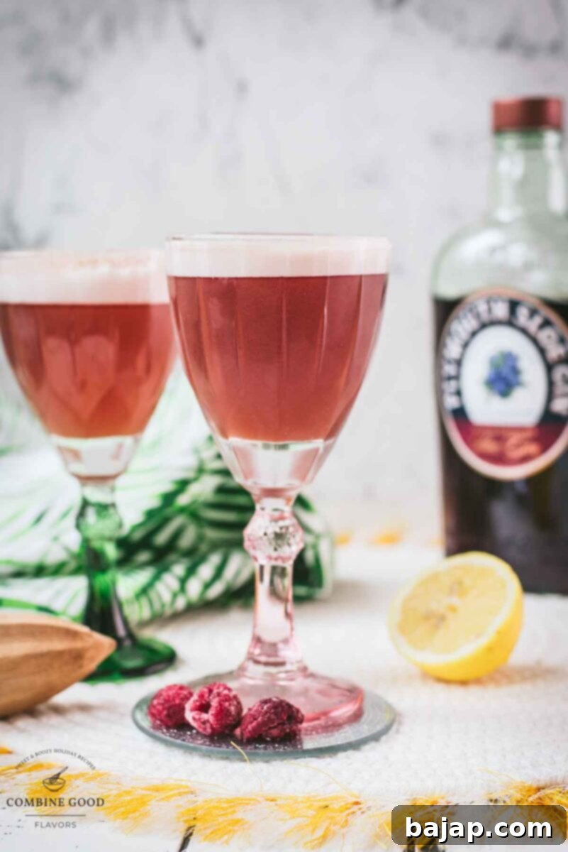 Divine ruby fizz cocktail, placed on mirrored coaster and served in a red and a green glass, showcasing the vibrant color and foam.