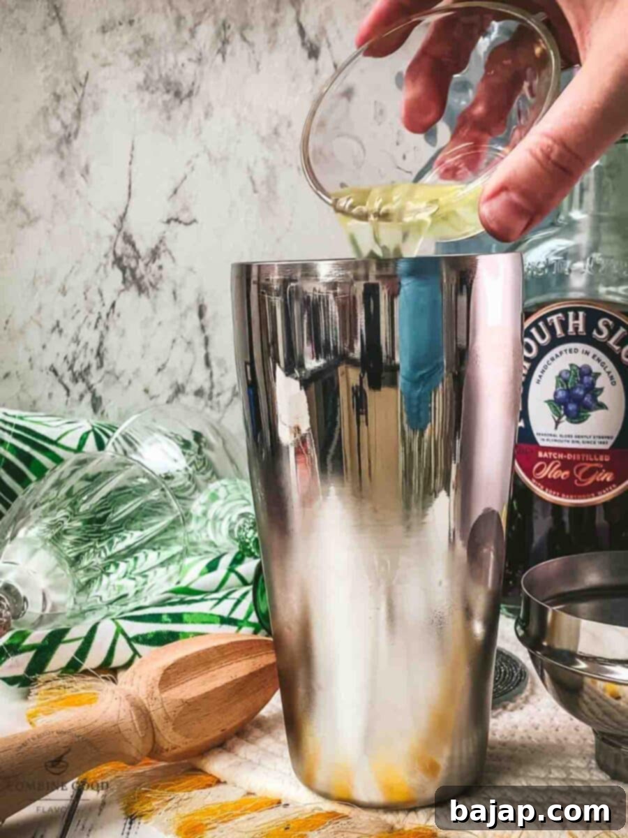 Carefully adding fresh egg white to the cocktail shaker, preparing for the frothy Ruby Fizz.