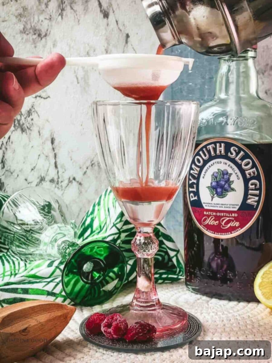 Fine straining the Ruby Fizz cocktail into the serving glasses to ensure a smooth texture and a beautiful foam.