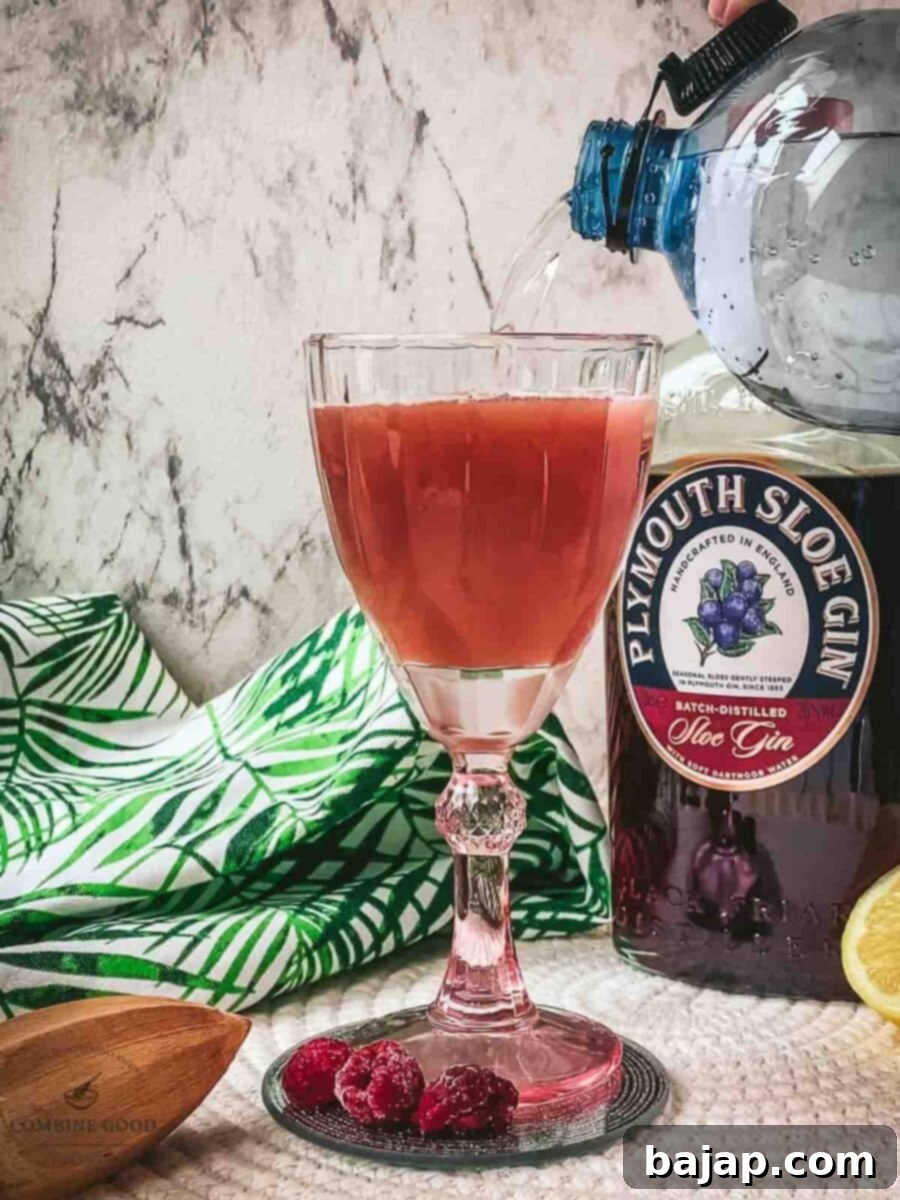 Topping the cocktail with sparkling water to create the fizz.