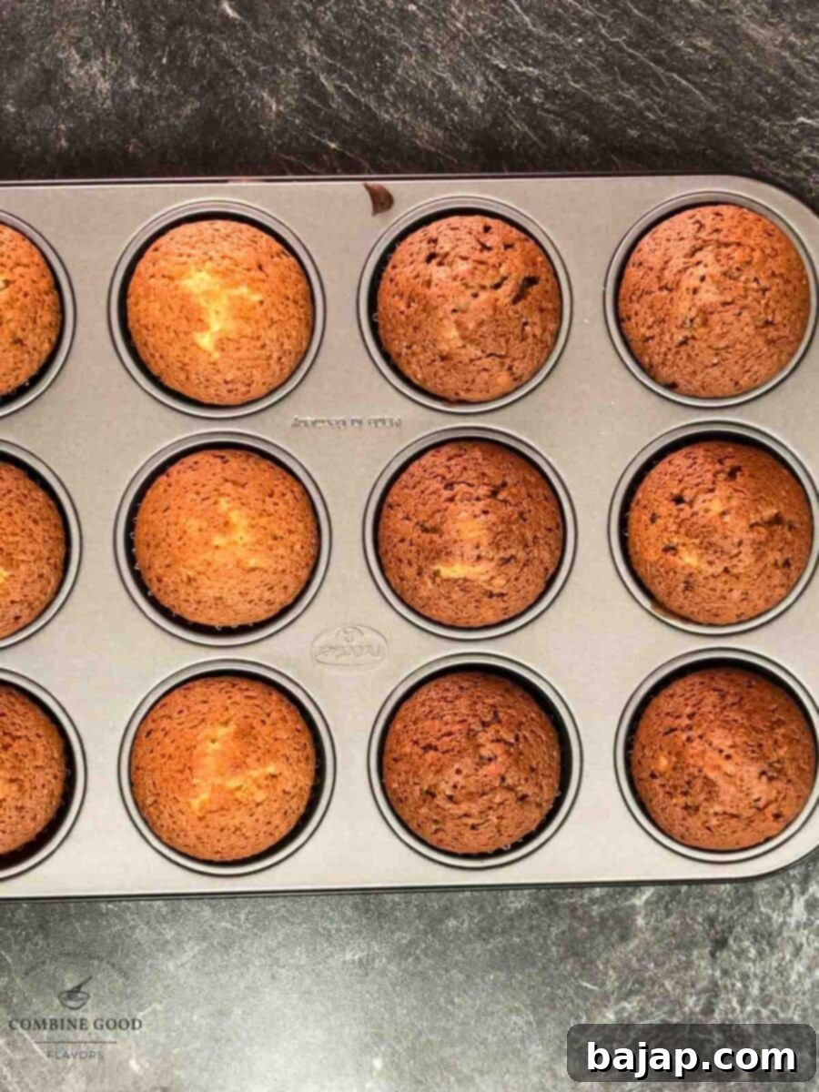 Freshly baked rum muffins arranged on a cooling rack, featuring both golden-brown plain muffins and rich dark cocoa muffins.