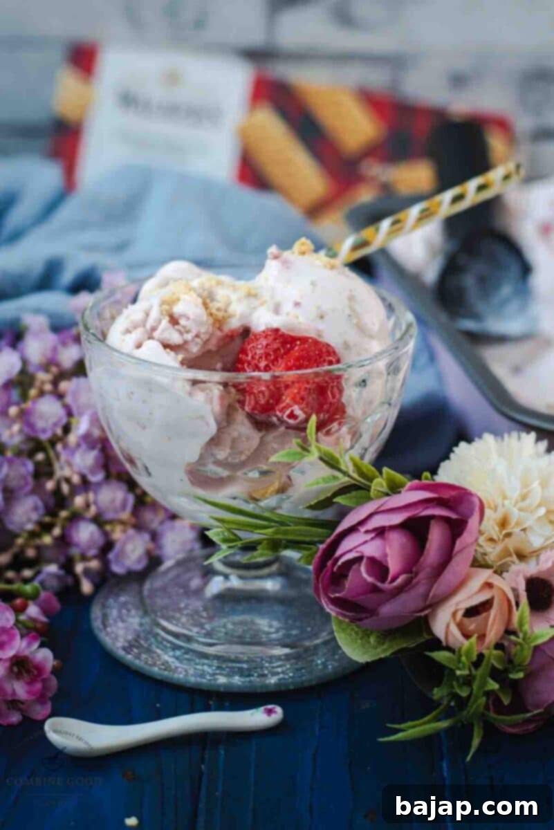 Glass serving bowl, filled with delicious strawberry shortcake ice cream. Garnished with fresh strawberries and shortbread cookie crumbs.