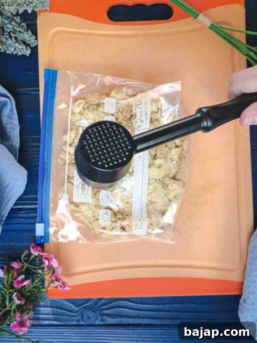 Crushing shortbread cookies in a ziplock bag. Using a meat tenderizer and a chopping board for support.