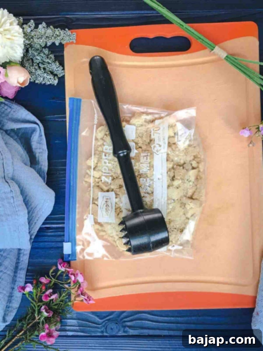 Crushed shortbread cookies in a ziplock bag. Using a meat tenderizer and a chopping board for support.