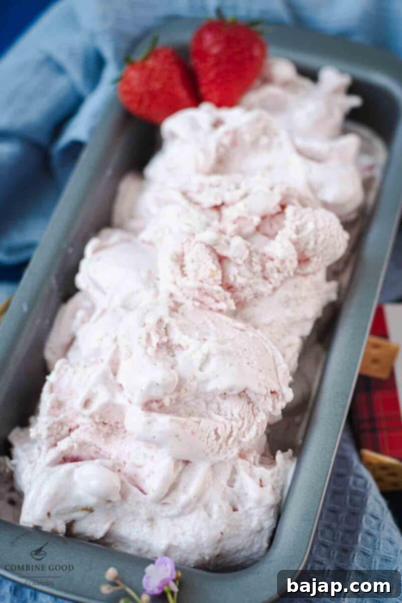 Glass serving bowl, filled with delicious strawberry shortcake ice cream. Garnished with fresh strawberries and shortbread cookie crumbs.