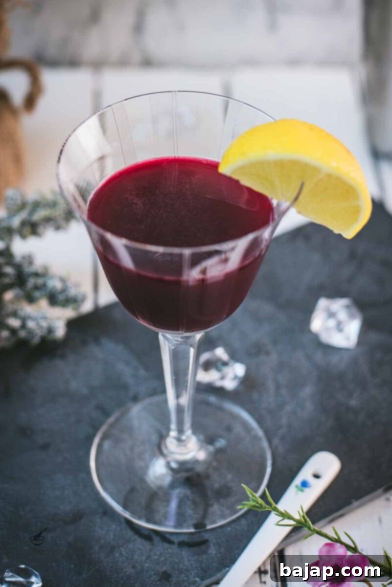 Elegant, dark red beetroot sour, garnished with a lemon wedge. Placed on a black slate plate.