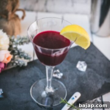 Elegant, dark red beetroot sour, garnished with a lemon wedge. Placed on a black slate plate.