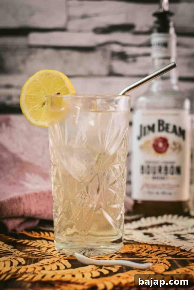 Batch Bourbon Highball prepared in a pitcher, ready for serving with lemon slices.