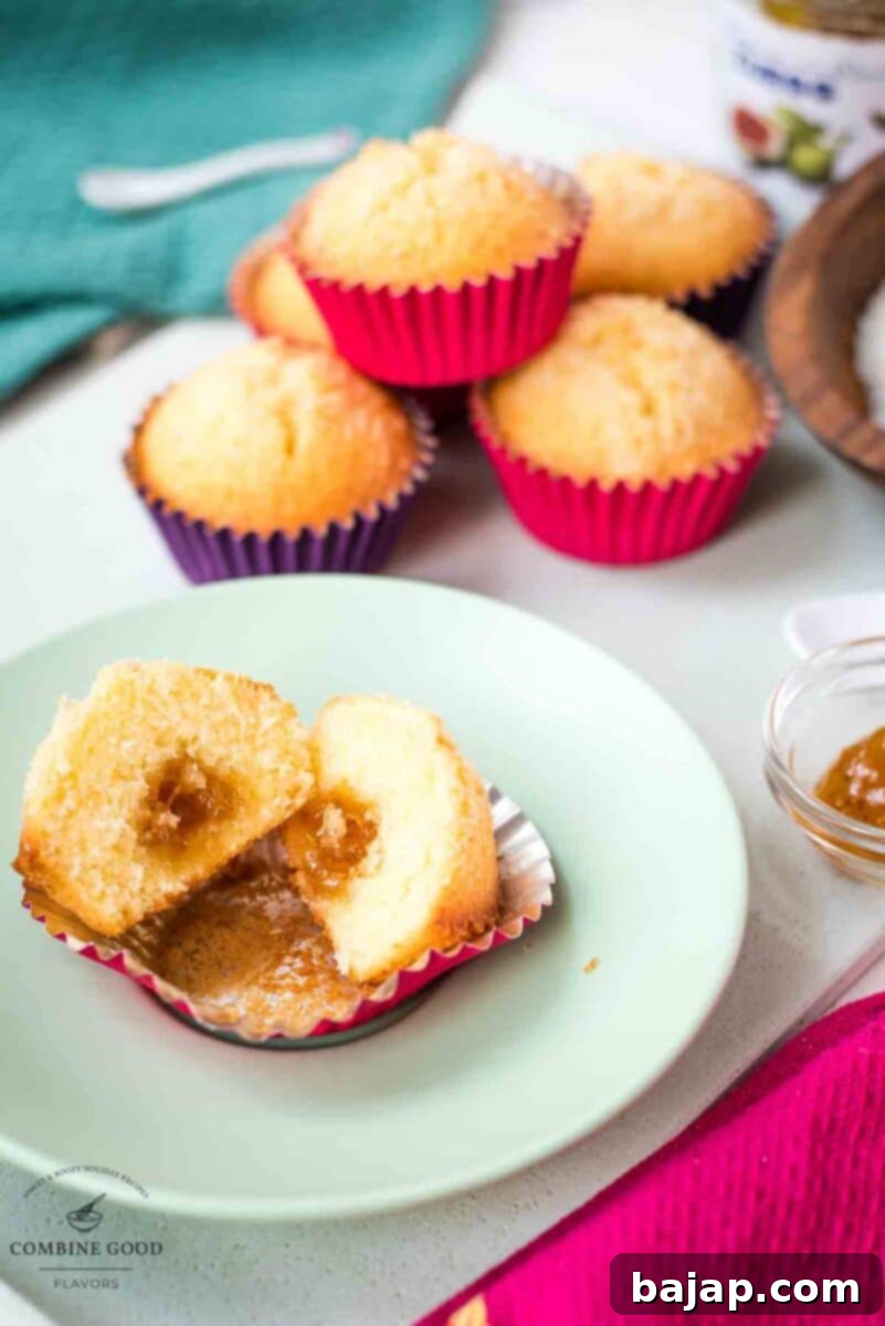 Halved coconut muffin revealing a gooey fig jam center, ready for a delicious bite.