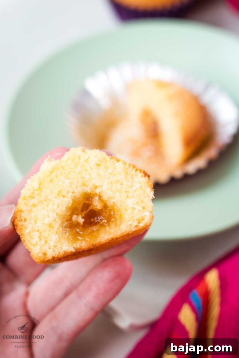 A close-up of a perfectly halved coconut muffin, with the glistening fig jam center prominently displayed.