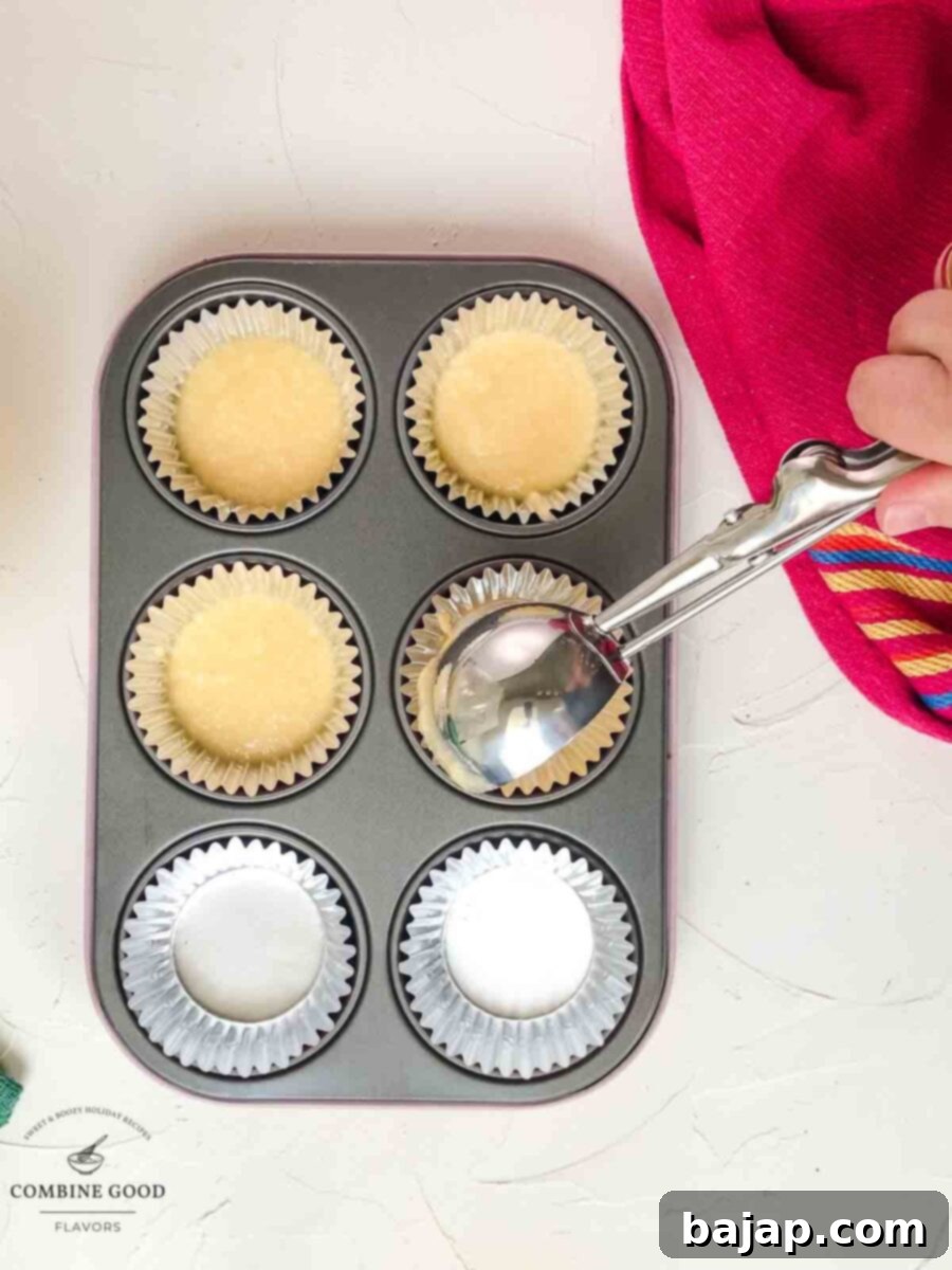Muffin tin with six cups partially filled with coconut muffin batter.