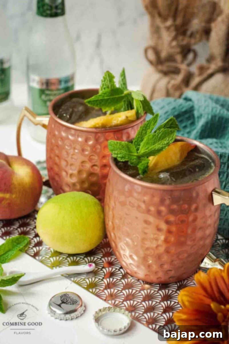 Delicious peach Moscow mule, served in copper mugs, garnished with peach slices and mint.